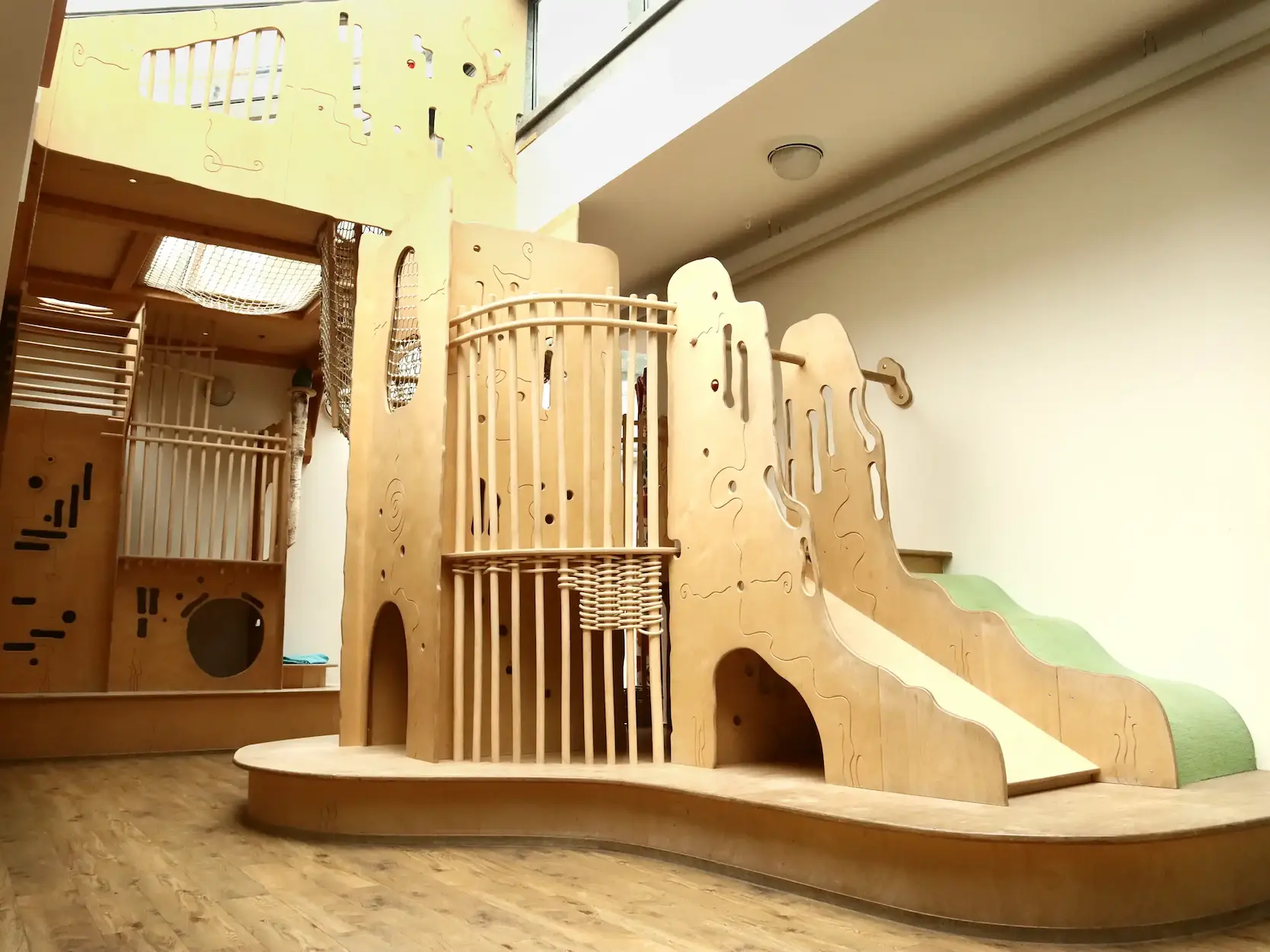 Helles Holz-Spielgerüst mit Rutsche im Innenbereich.