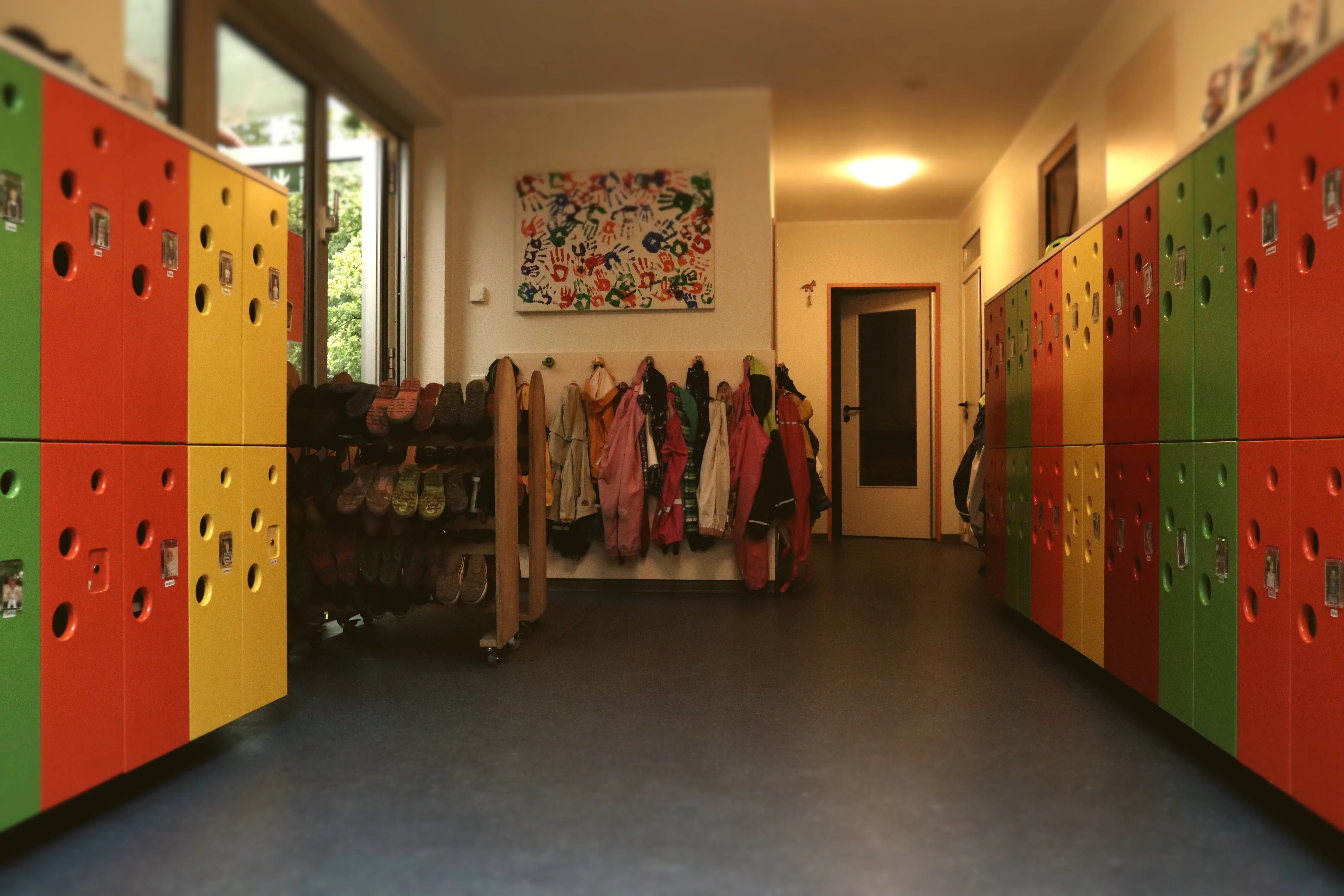 Farbenfroher Flur mit Kindergarderoben an der Wand. Die individuellen Garderobenfächer bieten jedem Kind seinen eigenen Platz für Jacken und Taschen.